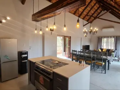 a kitchen and living room with a stove and a table at Hoedspruit Bush Stay in Hoedspruit