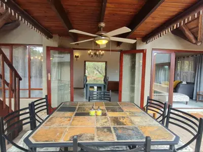 a dining room table with chairs and a ceiling fan at Hoedspruit Bush Stay in Hoedspruit