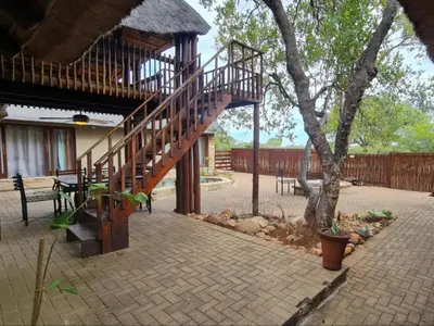a wooden staircase leading up to a house with a tree at Hoedspruit Bush Stay in Hoedspruit