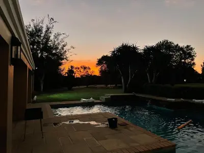 a swimming pool with a sunset in the background at Country living in the City in Midrand