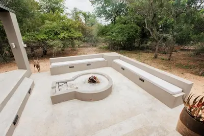 an outdoor fire pit on a patio with trees at Chawal Stays Swartwitpens in Marloth Park