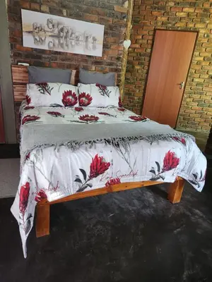 a bedroom with a bed with red flowers on it at Kudu Mal in Marloth Park