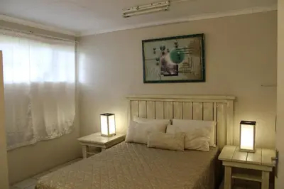 a bedroom with a bed and two lamps on tables at Montrose River Lodge in Schoemanskloof