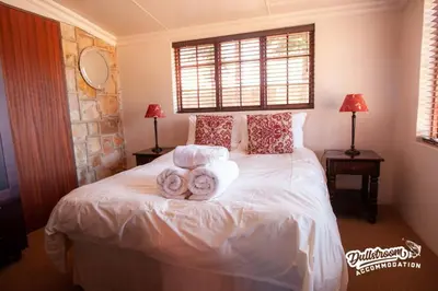 a bedroom with a white bed with towels on it at Duckling Cottage in Dullstroom