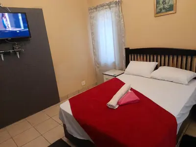 a bedroom with a bed with a red blanket and a tv at Cozy guesthouse-springs in Springs