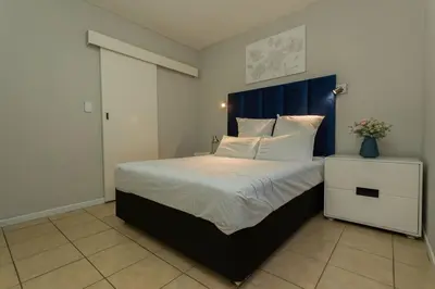 a bedroom with a large bed with a blue headboard at 15min to OR TAMBO perfect long stay WiFi & Netflix in Benoni