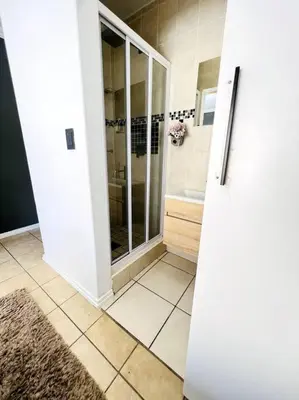 a white bathroom with a shower and a sink at 15min to OR TAMBO perfect long stay WiFi & Netflix in Benoni