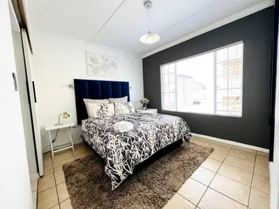 a bedroom with a black and white bed and a window at 15min to OR TAMBO perfect long stay WiFi & Netflix in Benoni
