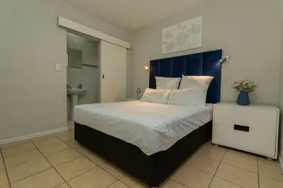 a bedroom with a large bed with a blue headboard at 15min to OR TAMBO perfect long stay WiFi & Netflix in Benoni