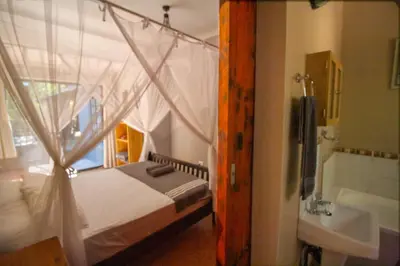 a bedroom with a bed and a tub and a sink at Kruger Park Hostel in Marloth Park