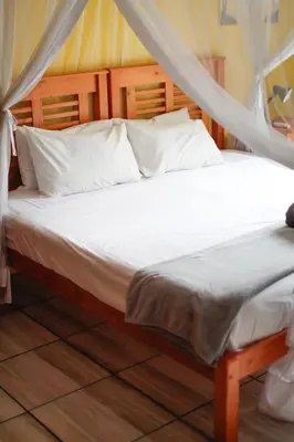 a bed with white sheets and pillows in a room at Kruger Park Hostel in Marloth Park