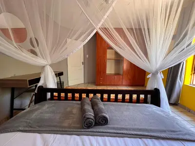 a bed with two rolled up towels on it at Kruger Park Hostel in Marloth Park