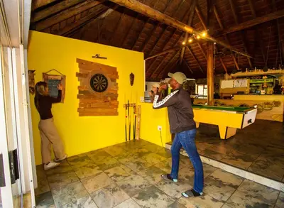 a man taking a picture of a woman playing pool at Kruger Park Hostel in Marloth Park