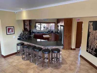 a kitchen with a counter with bar stools at Lodge on Watering Hole , Zebula in Mabula