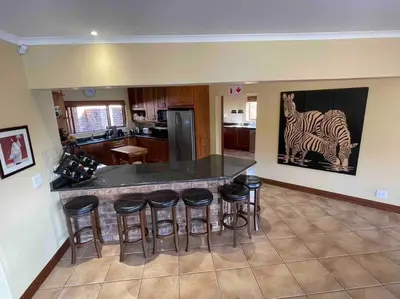 a kitchen with a bar with stools and a painting of a zebra at Lodge on Watering Hole , Zebula in Mabula