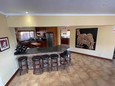 a kitchen with a bar with stools around it at Lodge on Watering Hole , Zebula in Mabula