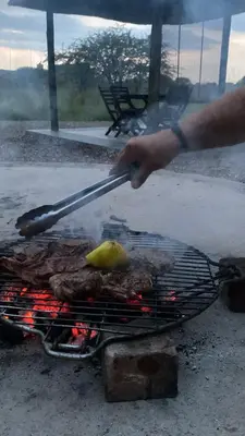 a person is cooking meat on a grill at Luna Piena 19A Zebula golf course and spa resort in Mabula