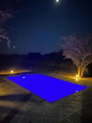 a blue swimming pool at night with a tree at Luna Piena 19A Zebula golf course and spa resort in Mabula