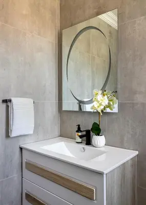 a bathroom with a white sink and a mirror at Woman Era Guest House in Midrand