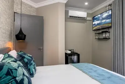 a bedroom with a bed and a tv on the wall at Woman Era Guest House in Midrand