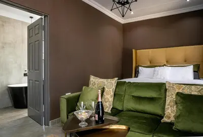 a living room with a green couch and a bed at Woman Era Guest House in Midrand