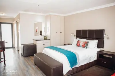 a bedroom with a large bed and a desk at Perfek Stay Guesthouse in Secunda