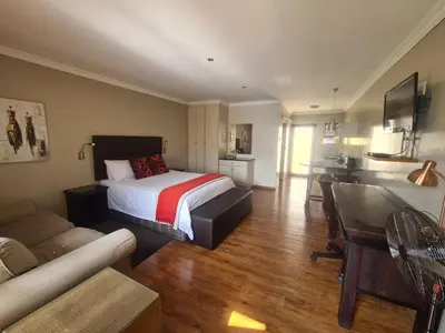 a bedroom with a bed and a living room at Perfek Stay Guesthouse in Secunda