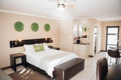 a bedroom with a large bed and a kitchen at Perfek Stay Guesthouse in Secunda