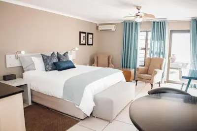 a bedroom with a large bed and a living room at Perfek Stay Guesthouse in Secunda
