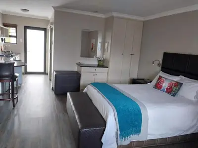 a bedroom with a large bed and a kitchen at Perfek Stay Guesthouse in Secunda