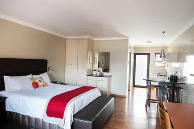a bedroom with a large bed and a kitchen at Perfek Stay Guesthouse in Secunda