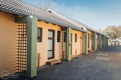 a row of houses with green columns on a street at Perfek Stay Guesthouse in Secunda
