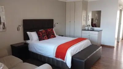 a bedroom with a large bed with a red blanket at Perfek Stay Guesthouse in Secunda
