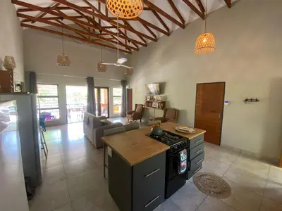 a kitchen with a stove and a living room at Sonador Bush House in Marloth Park
