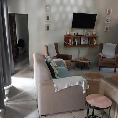 a living room with a couch and a tv at Sonador Bush House in Marloth Park