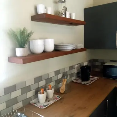 a kitchen with a counter with bowls and plates on shelves at Sonador Bush House in Marloth Park