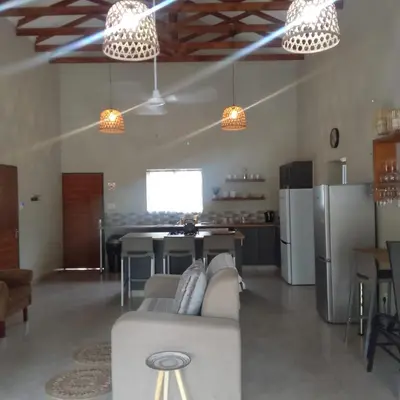 a living room with a couch and a table and refrigerator at Sonador Bush House in Marloth Park