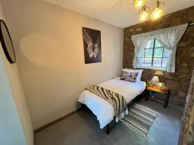 a small bedroom with a bed and a window at Ehlathini Game Lodge in Marken