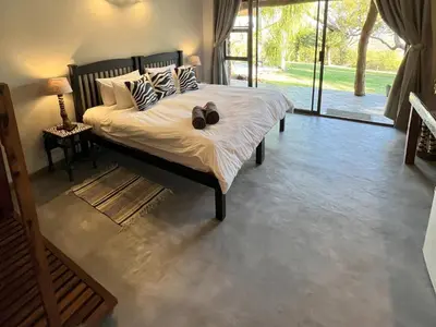 a bedroom with a bed with two shoes on it at Ehlathini Game Lodge in Marken