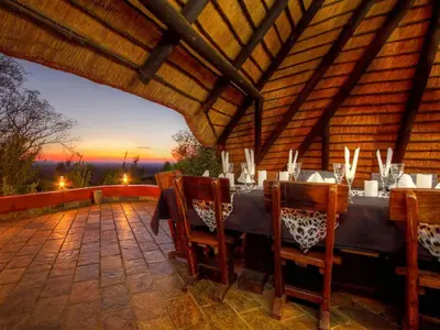 a dining table on a patio with a sunset in the background at Ehlathini Game Lodge in Marken