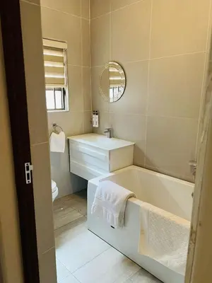 a bathroom with a tub and a sink and a mirror at Ultimate Sky _ 2 bedroom villa in Pretoria