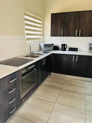 a kitchen with wooden cabinets and a sink at Ultimate Sky _ 2 bedroom villa in Pretoria