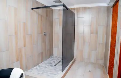 a shower with a glass door in a bathroom at TINDLOVU GUESTHOUSE in Nelspruit