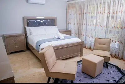 a small bedroom with a bed and a chair at TINDLOVU GUESTHOUSE in Nelspruit