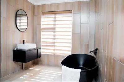 a bathroom with a black tub and a sink at TINDLOVU GUESTHOUSE in Nelspruit