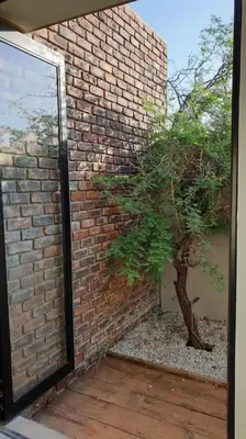 a brick wall with a tree next to a building at Lindi Lodge, Mjejane Game Reserve in Hectorspruit