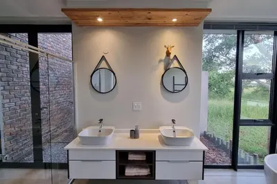 two sinks in a bathroom with two mirrors on the wall at Lindi Lodge, Mjejane Game Reserve in Hectorspruit