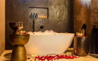 a bathroom with a bath tub with red flowers on the floor at NAKO Safari Lodge in Dinokeng Game Reserve