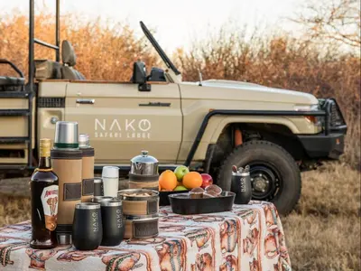 a table with food and drinks and a military truck at NAKO Safari Lodge in Dinokeng Game Reserve