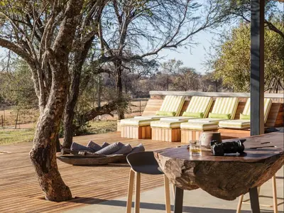 a patio with a tree and a table and chairs at NAKO Safari Lodge in Dinokeng Game Reserve